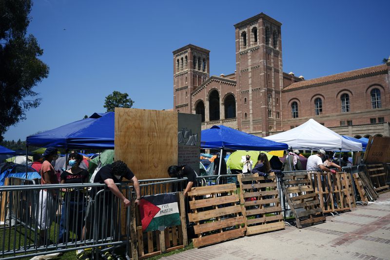 Demonstrators restore a protective barrier at an encampment on the UCLA campus, the morning after clashes between Pro-Israel and Pro-Palestinian groups, Wednesday, May 1, 2024, in Los Angeles. (AP Photo/Jae C. Hong)