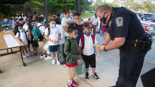 Lake City Georgia police officer J. Yancey hands out pencils on the first day of school at Lake City Elementary  Monday, August 2, 2021.STEVE SCHAEFER FOR THE ATLANTA JOURNAL-CONSTITUTION