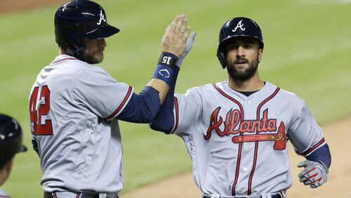 Atlanta Braves ' A.J. Pierzynski, left, high-fives Nick Markakis after both scored on base hit by Adonis Garcia during the eighth inning. (AP Photo/Alan Diaz)