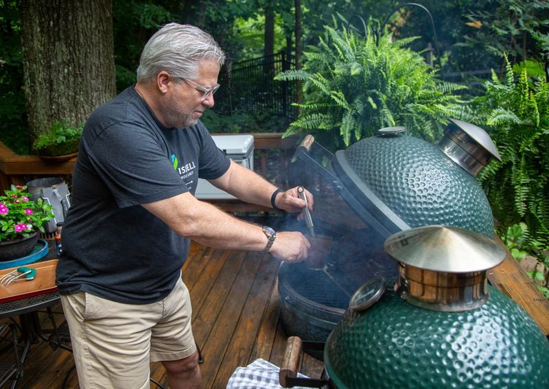 Hal Boyd cooks smoked pork on his Big Green Egg to make pulled pork sandwiches for healthcare workers at Piedmont Hospital at his North Druid Hills Home. He and his friends have made and delivered more than 4,000 BBQ sandwiches to area hospitals and other first responders since the pandemic began. PHIL SKINNER FOR THE ATLANTA JOURNAL-CONSTITUTION.