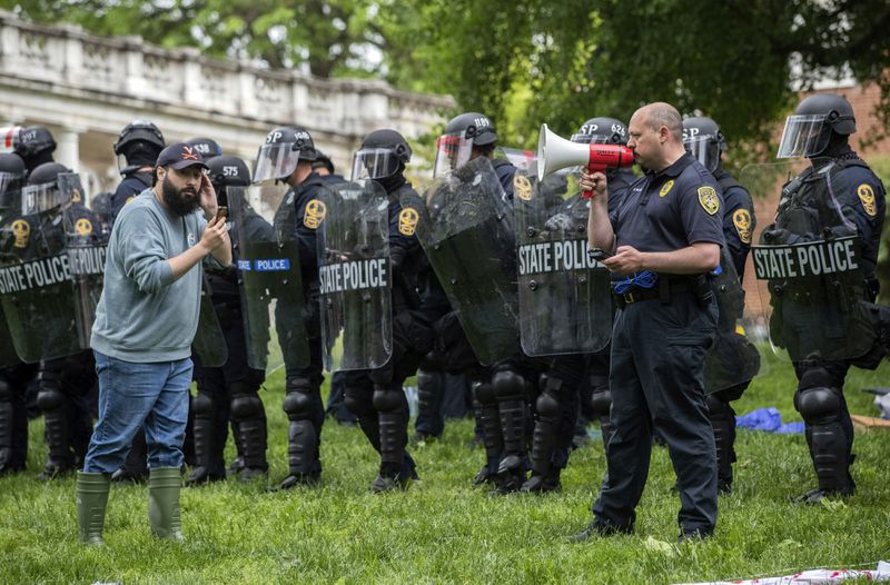 Police use a microphone as a pro-Palestinian protester listens on the grounds of the University of Virginia, in Charlottesville, Va., where tents were set up, Saturday, May 4, 2024. (Cal Cary/The Daily Progress via AP)