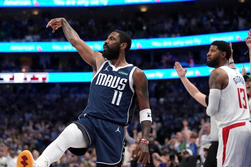 Dallas Mavericks guard Kyrie Irving (11) follows through on a 3-point basket as Los Angeles Clippers forward Paul George (13) looks on during the second half of Game 4 of an NBA basketball first-round playoff series Sunday, April 28, 2024, in Dallas. (AP Photo/Jeffrey McWhorter)