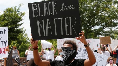Atlanta Hawks guard Trae Young, right, holds a "Black Lives Matter" sign at a peaceful rally Monday, June 1, 2020, in his hometown of Norman, Okla., calling attention to the killing of George Floyd by Minneapolis police on May 25. (AP Photo/Sue Ogrocki)