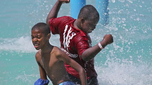 Malik Ambles, left, 11, and Jesse Sands, 12, right, feel the coolness of the water spray at Clayton County International Park in summer 2012. JOHN SPINK / JSPINK@AJC.COM