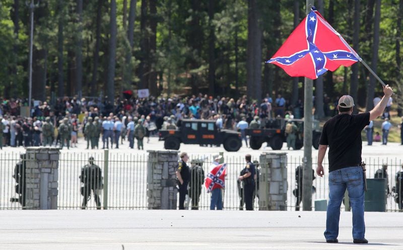 April 23, 2016 Stone Mountain: Joseph Andrews, one of a small group with the Rock Stone Mountain rally, waves a confederate battle flag towards a mass of counter-protesters more than 100 yards away at Stone Mountain Park on Saturday afternoon April 23, 2016 where a white power protest and two counter protests were scheduled. Ben Gray / bgray@ajc.com