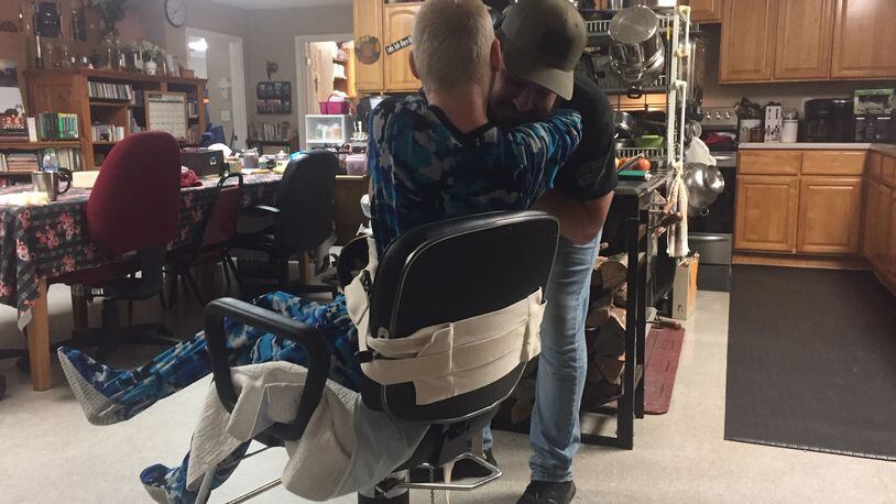 Logan Fahey, the biological son of the founders of The King's Cleft ministry, hugs Jayden Fahey, 21, on Thursday while he is strapped to a chair for his own protection. Jayden has Angelman syndrome, a genetic disorder. (Johnny Edwards / Johnny.Edwards@ajc.com)