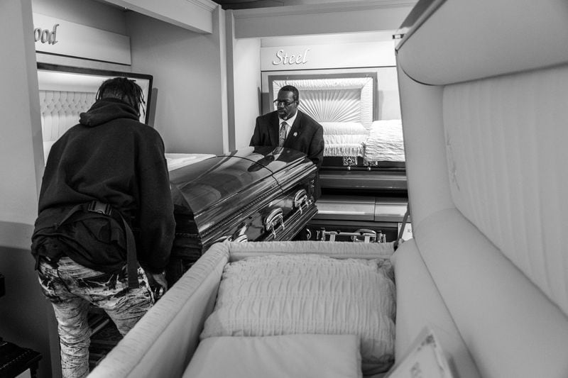 Eric Lancaster (left) and Jarvis Williams move a new casket into the display room of the Willie Watkins Funeral Home in the West End. 