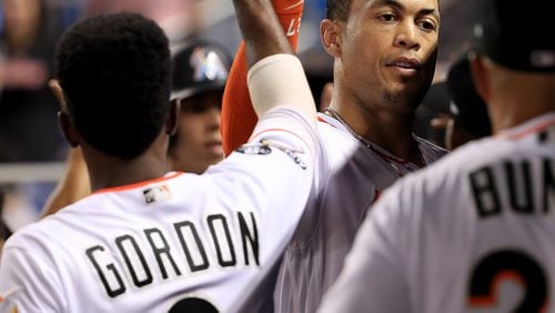 Giancarlo Stanton is congratulated after drawing a walk and scoring in the third inning Thursday against the Braves. He hit two home runs in the game.  (Photo by Mike Ehrmann/Getty Images)