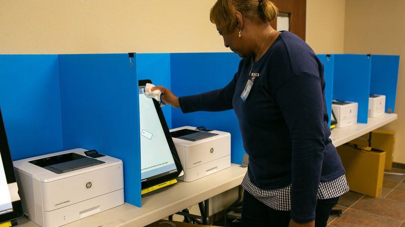 A polling assistant cleans a voting machine at the Paulding County Municipal Building on Oct. 14 in Dallas, Ga. Paulding and six other counties were the first to test the new machines that will be in all precincts in the state for the March 24 presidential primary election. (Photo/Rebecca Wright for the Atlanta Journal-Constitution)
