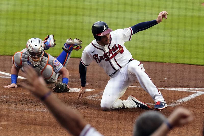 Atlanta Braves' Freddie Freeman (5) beats the tag from New York Mets catcher James McCann (33) to score on an Ozzie Albies base hit in the first inning of a baseball game Wednesday, June 30, 2021, in Atlanta. (AP Photo/John Bazemore)