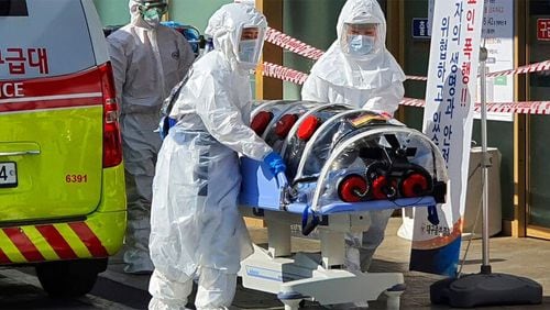 In this Wednesday, Feb. 19, 2020, photo, medial workers wearing protective gears move a patient suspected of contracting the new coronavirus from an ambulance to the Kyungpook National University Hospital in Daegu, South Korea.