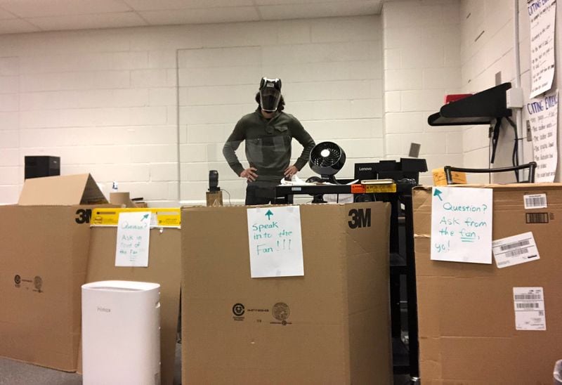 Ryan Proffitt, a 39-year-old language arts teacher at Lanier High School in Gwinnett who is suffering from long-term effects of COVID-19. In his classroom, he has boxes surrounding his desk to socially distance from students.  (Courtesy photo)