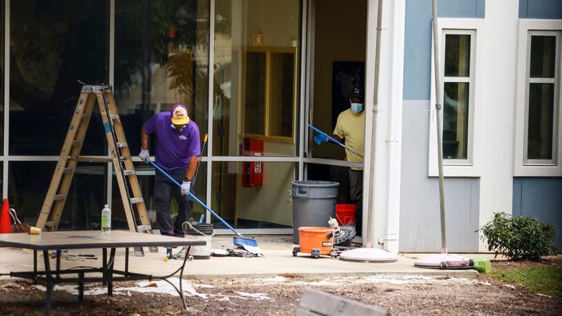 Workers sweep up glass and debris from a broken window at At-Promise Youth Center on Friday, May 27 2022. (Natrice Miller / natrice.miller@ajc.com)