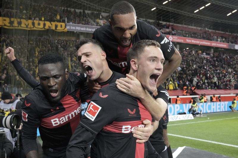 FILE - Leverkusen's Florian Wirtz, right, celebrates with teammates Jonathan Tah, up, Victor Boniface, left, and Granit Xhaka, centre, after scoring a goal that was seconds later disallowed by a VAR decision during the German Bundesliga soccer match between Bayer Leverkusen and Borussia Dortmund at the BayArena in Leverkusen, Germany, on Dec. 3, 2023. Excitement was building in Leverkusen, Germany on Sunday ahead of local team Bayer Leverkusen’s expected Bundesliga title win after an outstanding season so far. (AP Photo/Martin Meissner, File)