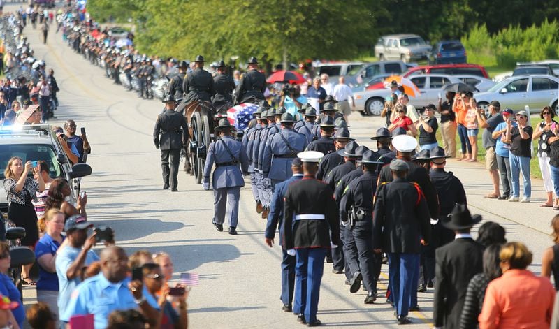 An honor escort and family members follow a caisson carrying the flag-draped coffin of Griffin police Officer Kevin “Shogun” Dorian Jordan, 43, to Westwood Gardens Cemetery on June 9, 2014, in Griffin. CURTIS COMPTON / CCOMPTON@AJC.COM