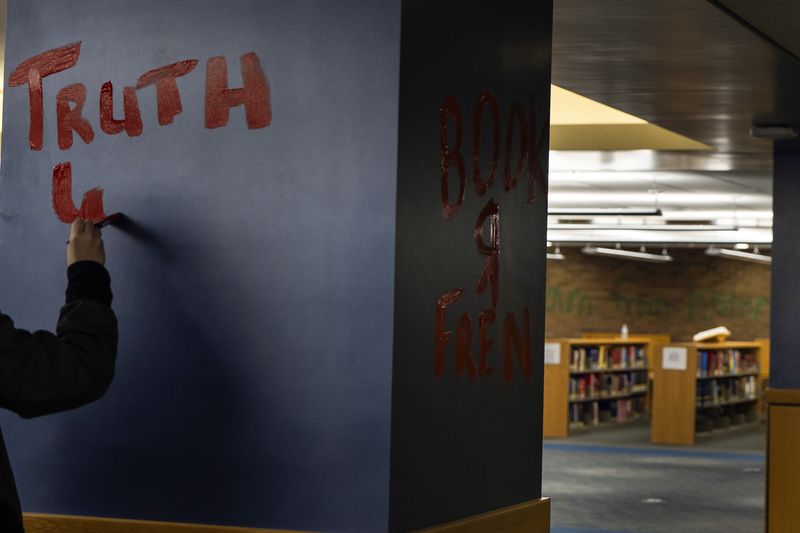 A pro-Palestinian protester paints on a column at Millar Library on the Portland State University campus Wednesday, May 1, 2024, in Portland, Ore. (AP Photo/Jenny Kane)