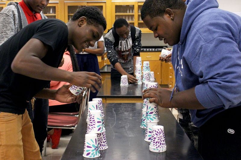 Carver High School students Nicholas Neal and I-Tavious Scott, left to right, race to put the cups up for their project in which they create graphs based on their timing at S.T.E.A.M. Academy at Carver High School on Aug. 2. Jenna Eason / Jenna.Eason@coxinc.com