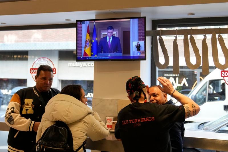 Customers have breakfast in a restaurant while Spanish Prime Minister Pedro Sanchez appears on a television broadcast in Madrid, Spain, Monday, April 29, 2024. Sánchez says he will continue in office "even with more strength" after days of reflection. Sánchez shocked the country last week when he said he was taking five days off to think about his future after a court opened preliminary proceedings against his wife on corruption allegations. (AP Photo/Paul White)
