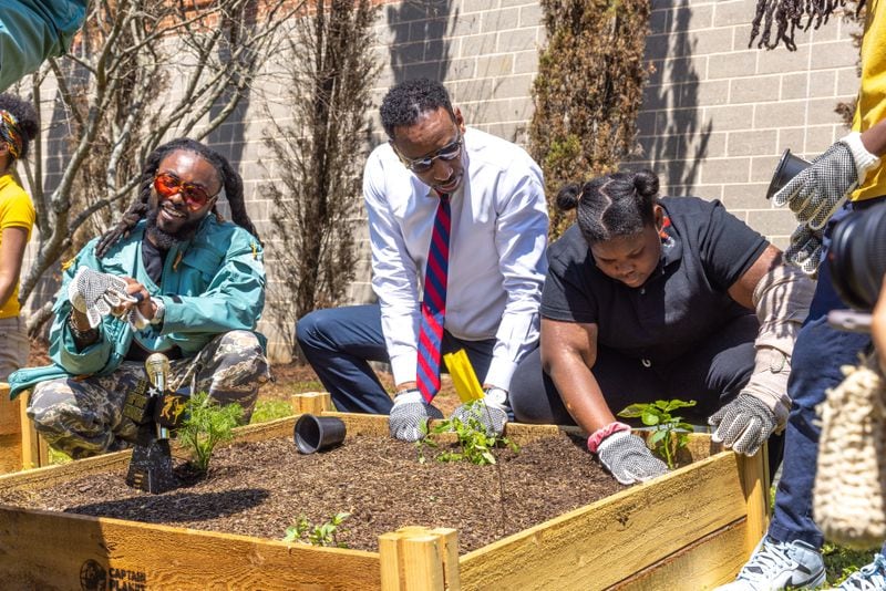 Olu aka Johnny Venus, Mayor Andre Dickens, and a student garden in a new community garden at Jean Childs Young Middle School in Atlanta on Thursday, March 30, 2023. Olu and WowGr8 aka Doctur Dot of hip-hop group EARTHGANG helped sponsor the project. (Arvin Temkar / arvin.temkar@ajc.com)