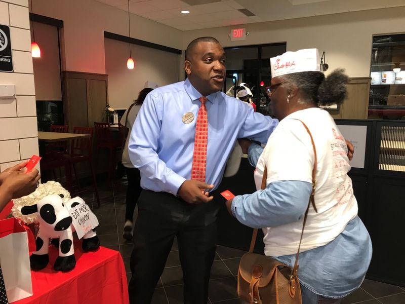 Chick-fil-A franchise operator Rory Woodfaulk hands out gift cards for a one-year supply of free meals to the first 100 people who in lineD overnight to be his first customers on opening day. LIGAYA FIGUERAS / LIGAYA.FIGUERAS@AJC.COM