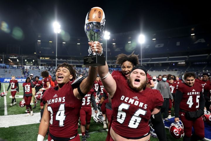Warner Robins players Ahmad Walker (34) and Bobby Hutchinson (66) celebrate with the trophy after their 62-28 win against against Cartersville in the Class 5A state high school football final at Center Parc Stadium Wednesday, December 30, 2020 in Atlanta. JASON GETZ FOR THE ATLANTA JOURNAL-CONSTITUTION