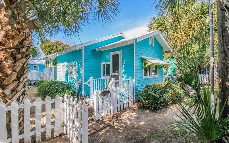 This old-school 1920's beach cottage on Tybee's original cottage row has a tin roof and a white picket-fenced yard – all less than 100 steps from the beach!