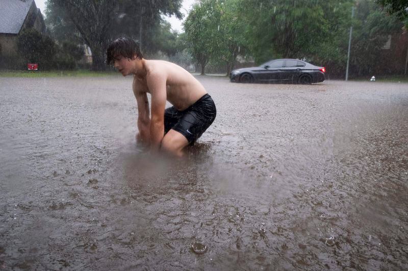 Nathan Duekero tries to unclog a storm drain during a severe storm, Thursday, May 2, 2024, in Spring, Texas. (Brett Coomer/Houston Chronicle via AP)