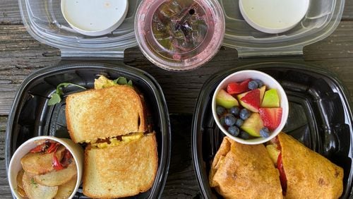 A takeout breakfast from Poach Social in Summerhill includes s sausage and egg sandwich with potatoes and a breakfast burrito with fruit. In the center is the One Love, a spicy, house-made sorrel drink. 
Wendell Brock for The Atlanta Journal-Constitution