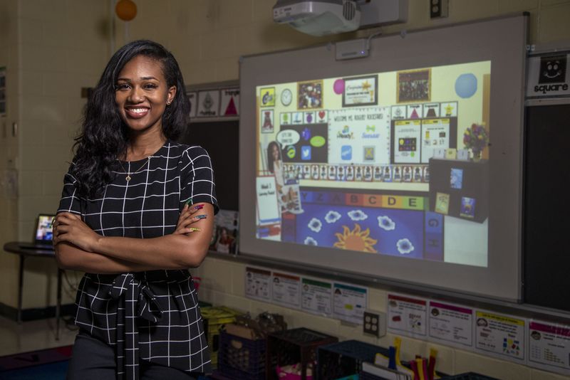 Love T. Nolan Elementary School first grade teacher Tori Rogers stands for portrait as her virtual classroom is projected on a board inside her physical classroom in Atlanta on August 13. (ALYSSA POINTER / ALYSSA.POINTER@AJC.COM)