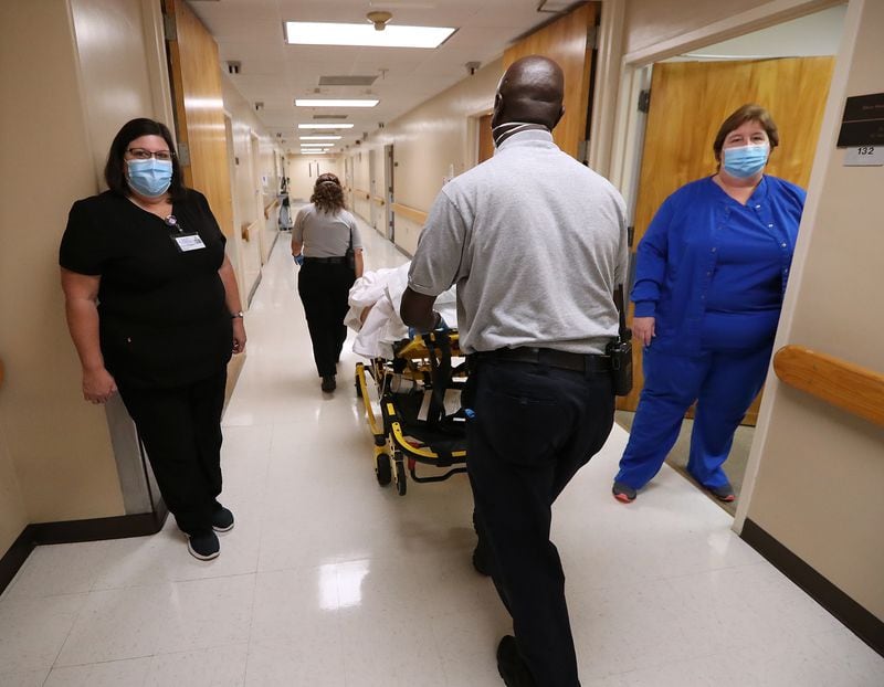 Medical staff at Elbert Memorial Hospital move aside for an EMS team wheeling a patient down the hall of the acute care unit. (Curtis Compton / Curtis.Compton@ajc.com)