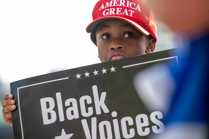 11/05/2020 —  Atlanta, Georgia — Gabriel McGee-Smoot, 8, shows support for President Donald Trump by holding a sign during a rally outside of State Farm Arena in downtown Atlanta, Thursday, November 5, 2020. Inside State Farm Arena, workers were busy finishing up the process of counting ballots from Fulton County voters. (Alyssa Pointer / Alyssa.Pointer@ajc.com)