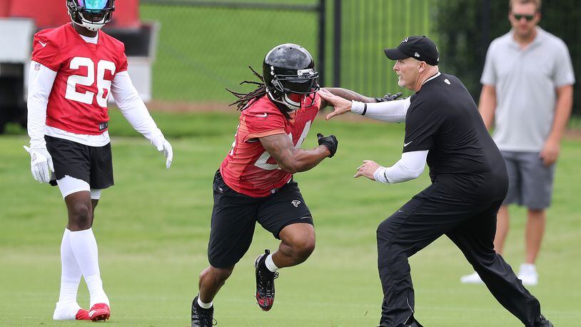 Atlanta Falcons head coach Dan Quinn blocks Devonta Freeman while working with the running backs with Tevin Coleman looking on during organized team activity on Wednesday, May 30, 2018, in Flowery Branch.  Curtis Compton/ccompton@ajc.com