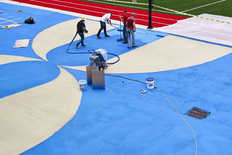 Workers with Streetbond apply a reflective paint to the basketball court at the SAE School in Mableton to reduce heat on Thursday, August 25, 2022. (Natrice Miller/ natrice.miller@ajc.com)