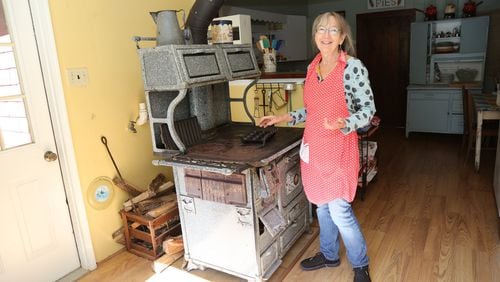 Barbara Swell stands beside the 1928 wood stove she uses to teach cooking classes in her log cabin in Asheville, N.C. Swell is the author of 11 cookbooks that feature recipes from the 19th and 20th centuries. She continues to collect South Appalachian recipes, oral histories and folklore from longtime mountain residents. TYSON HORNE / TYSON.HORNE@AJC.COM