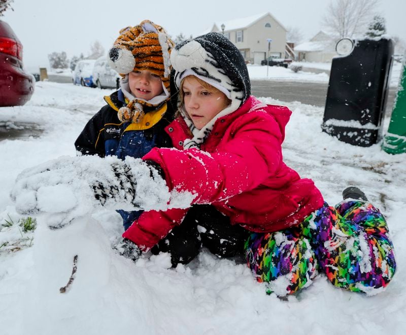 Leane Kinney, 11, and her brother, Aidan, 8, build a snowman in front of their home Monday morning, Nov. 17 in Trenton. Nick Graham / Staff