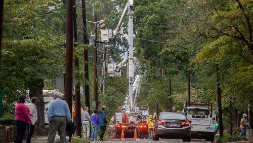 Residents walk on Adair Street as workers from Utility Lines Construction Services, a Delaware based company, work to restore power, Tuesday, Sept. 12, 2017, in Decatur, Ga.  BRANDEN CAMP/SPECIAL