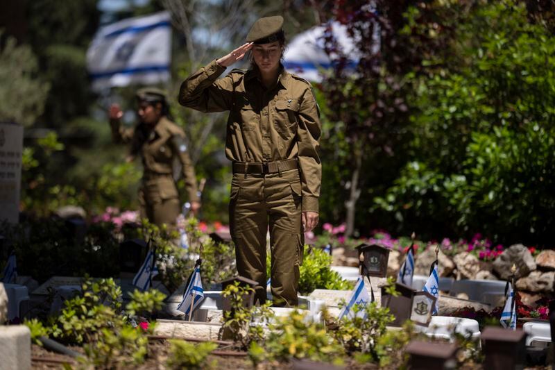 An Israeli soldier salutes after placing a flag with black ribbons on the grave of a soldier ahead of the country's memorial day for fallen soldiers at the Mount Herzl military cemetery in Jerusalem, Isreal, Wednesday, May 8, 2024. Israel marks the annual Memorial Day in remembrance of soldiers who died in the nation's conflicts. (AP Photo/Leo Correa)