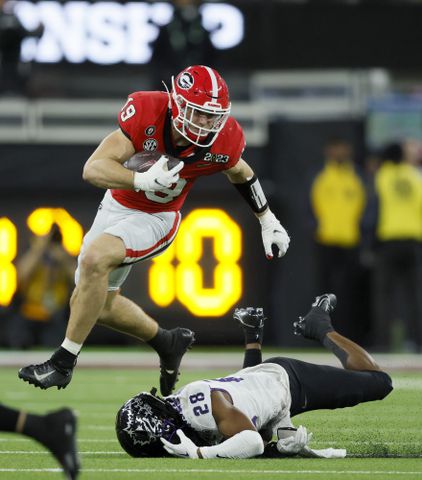 Georgia Bulldogs tight end Brock Bowers (19) runs over TCU Horned Frogs safety Millard Bradford (28) during the second half of the College Football Playoff National Championship at SoFi Stadium in Los Angeles on Monday, January 9, 2023. Georgia won 65-7 and secured a back-to-back championship. (Jason Getz / Jason.Getz@ajc.com)