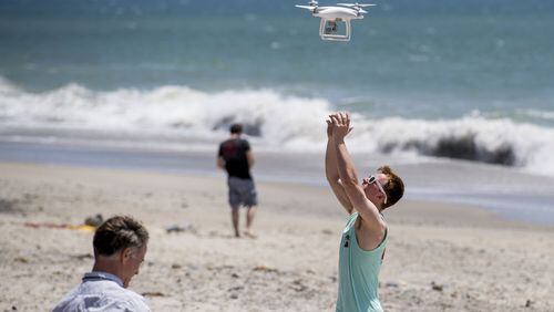 Joe Bell, right, of San Clemente, Calif. reaches to recover a drone controlled by his father, Russell, left, on Thursday, May 11, 2017 at Capistrano Beach in Dana Point. The pair were trying to spot sharks in the surf. (Paul Rodriguez/Orange County Register/TNS)