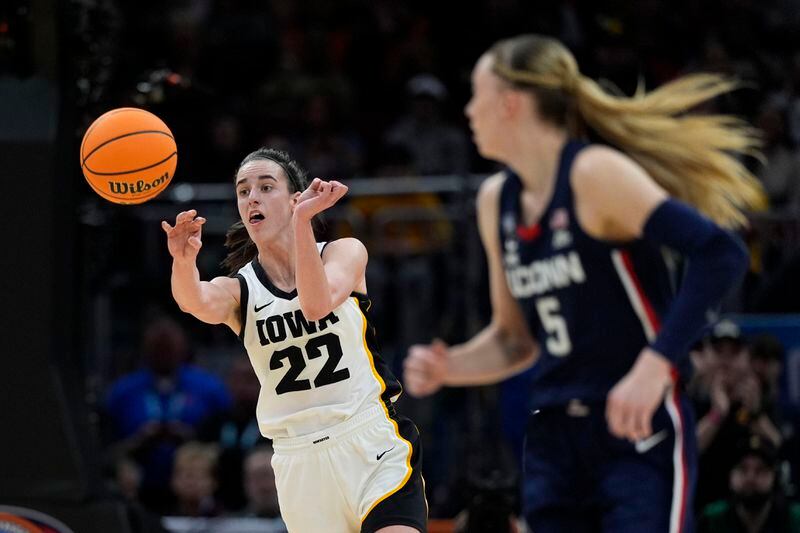 Iowa guard Caitlin Clark (22) passes up court in front of UConn guard Paige Bueckers (5) during the first half of a Final Four college basketball game in the women's NCAA Tournament, Friday, April 5, 2024, in Cleveland. (AP Photo/Carolyn Kaster)