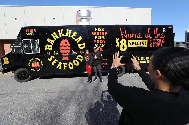 Chaka Dakers snaps a photo of Nichola Hines and Scott Fuller with the brand-new Bankhead Seafood food truck during a kickoff event for the business at Frederick Douglass High School on Thursday, Feb. 27, 2020, in Atlanta. The food truck is expected to hit Atlanta streets in late March or early April, while the restaurant’s reopening is planned for early 2021. CURTIS COMPTON / CCOMPTON@AJC.COM
