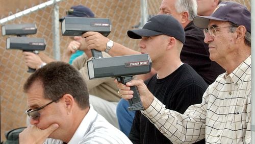 Pro scouts check pitch speeds at a Georgia high school game. (AJC file photo)