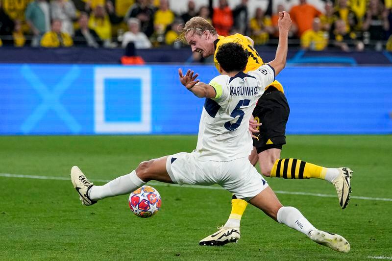 PSG's Marquinhos, front, defenses against Dortmund's Julian Brandt during the Champions League semifinal first leg soccer match between Borussia Dortmund and Paris Saint-Germain at the Signal-Iduna Park in Dortmund, Germany, Wednesday, May 1, 2024. (AP Photo/Martin Meissner)