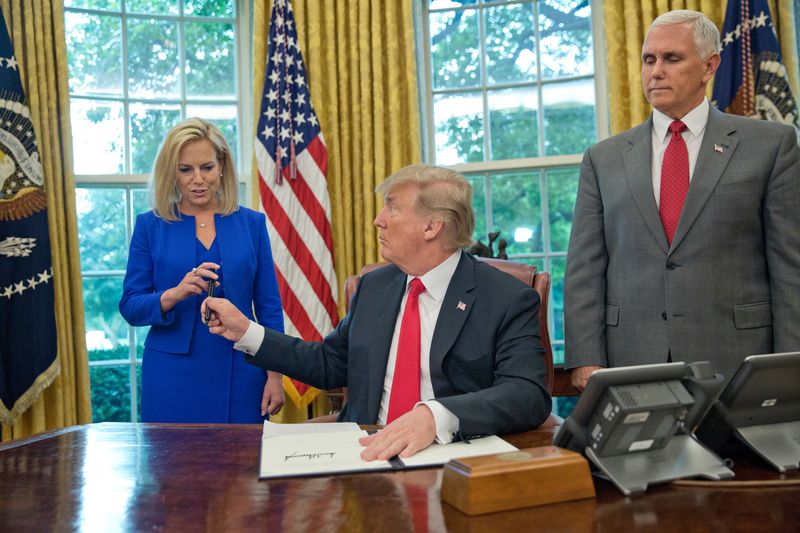 In this June 20, 2018, photo, President Donald Trump gives the pen he used to sign the executive order to end family separations at the border to Homeland Security Secretary Kirstjen Nielsen, left, as Vice President Mike Pence, right, watches in the Oval Office of the White House in Washington. Nielsen has one hard-earned presidential signing pen, receiving hers after Trump used it to sign the executive order. By the time Trump reversed his policy Wednesday, Nielsen had been both yelled at and praised by Trump and pilloried for repeating his falsehoods. (AP Photo/Pablo Martinez Monsivais)