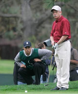 Tiger Woods works to line up a putt as caddy for contest winner John Abel, South Course at Torrey Pines, San Diego, California in October 2008.