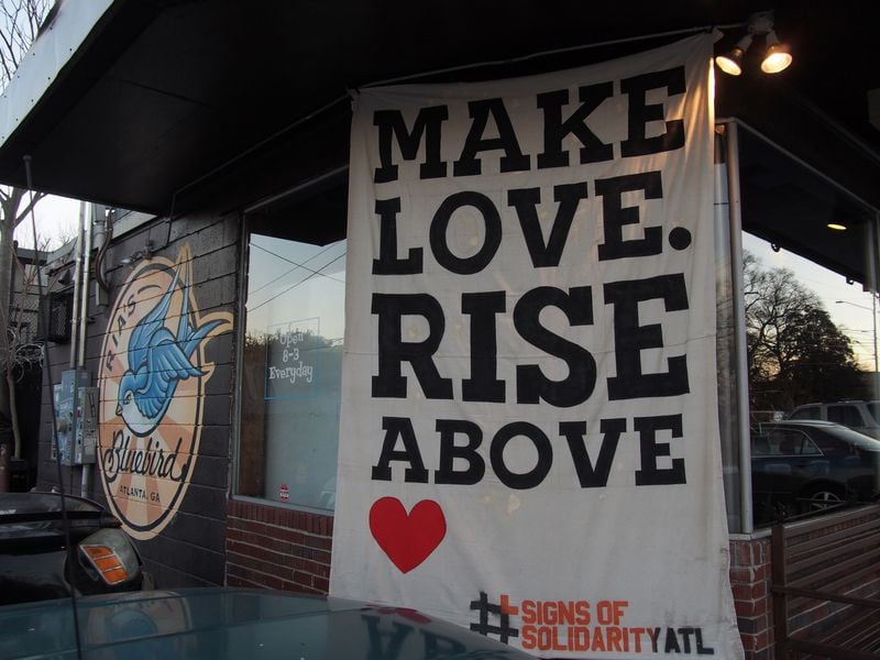 “Make Love, Rise Above,” suggests the banner on Rhia’s Bluebird cafe across from Oakland Cemetery. It was created by Soap Goods Creative for the Signs of Solidarity project. Photo: Modou Jallow
