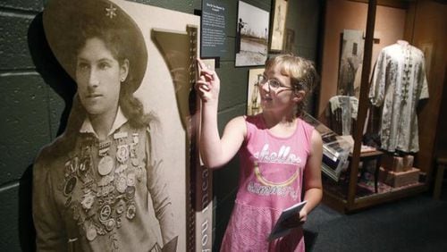 Alexis Stump of Union City, Indiana, compares her own height to a life-sized cutout of Annie Oakley at The Annie Oakley Center in Greenville, Ohio. The museum will offer free admission Saturday for Museum Day.