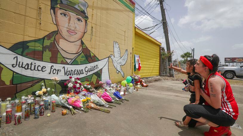 Dawn Gomez holds her 3-year-old granddaughter, Saryia Greer, who waves at Vanessa Guillen's mural painted by Alejandro "Donkeeboy" Roman Jr. on the side of Taqueria Del Sol, Thursday, July 2, 2020, in Houston. Army investigators believe Guillen, a Texas soldier missing since April, was killed by another soldier on the Texas base where they served, the attorney for the missing soldier's family said Thursday. (Steve Gonzales/Houston Chronicle via AP)