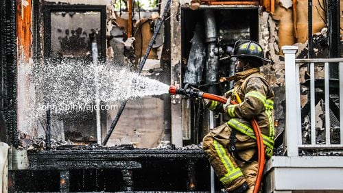 DeKalb County firefighter D’Ante Pickett sprays the upper floors of a building that caught on fire at the Northlake Manor Condominiums in Tucker on Friday morning.