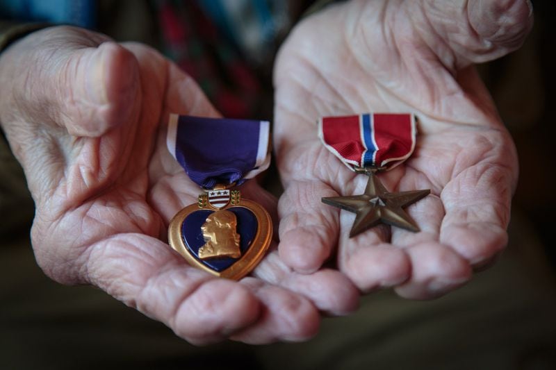 Josiah Benator holds his Purple Heart and Bronze Star Medal he received while serving in the WWII at his Atlanta home Friday, April 7, 2017. Benator has also overseen 53 Boy Scouts as they received their Eagle Scout rank during his 60 plus years as a scoutmaster. STEVE SCHAEFER / SPECIAL TO THE AJC